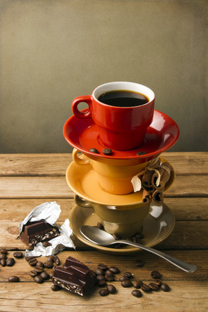 Colorful cups with coffee on wooden tabletop against grunge wallの写真素材
