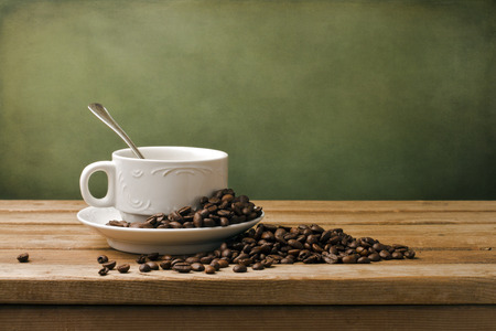 White cup and coffee beans on wooden table and grunge backgroundの写真素材