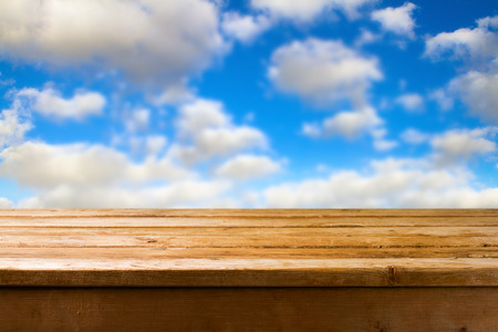 Background with beautiful blue sky and wooden deck tabletopの写真素材