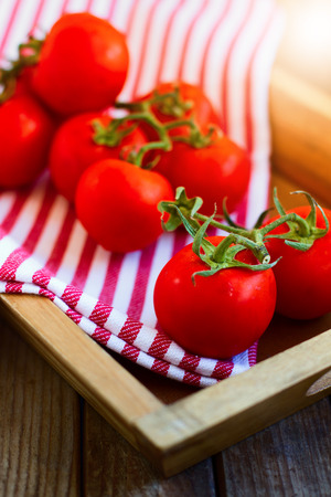 Fresh tomatoes in wooden tray on wooden tabletopの写真素材