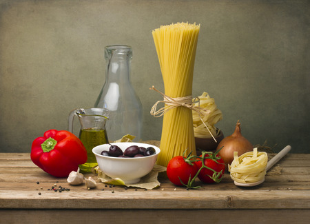 Italian food concept. Pasta and vegetables on wooden tabletop against grunge wall.の写真素材