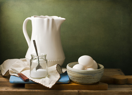Still life with white pitcher, eggs and salt on wooden tabletop against grunge wallの写真素材