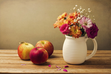 Beautiful flower bouquet and fresh apples on wooden tabletopの写真素材
