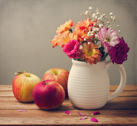 Beautiful flower bouquet and fresh apples on wooden tabletopの写真素材