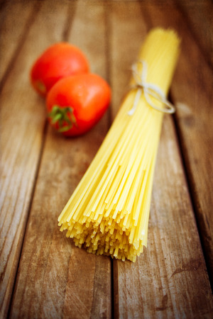 Pasta and tomatoes on vintage wooden table with grunge textureの写真素材