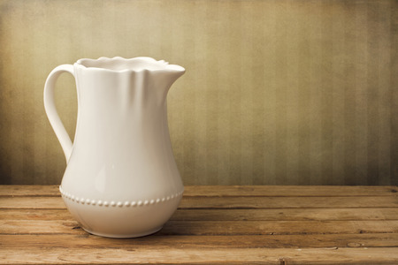 White jug on wooden table over grunge vintage backgroundの写真素材