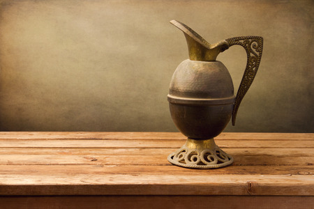 Vintage jug on wooden table over grunge backgroundの写真素材