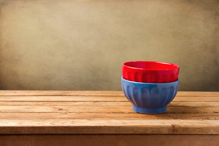 Colorful empty bowls on wooden table over grunge wallの写真素材