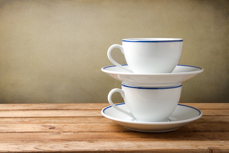 Two coffee cups on wooden tabletop against grunge backgroundの写真素材