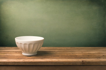 Grunge background with white bowl on wooden tableの写真素材