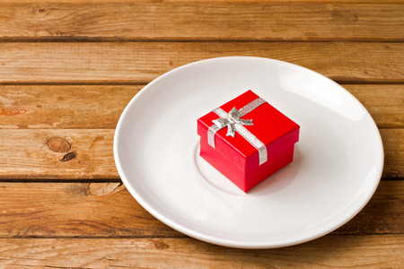 White plate with red gift box on wooden tableの写真素材