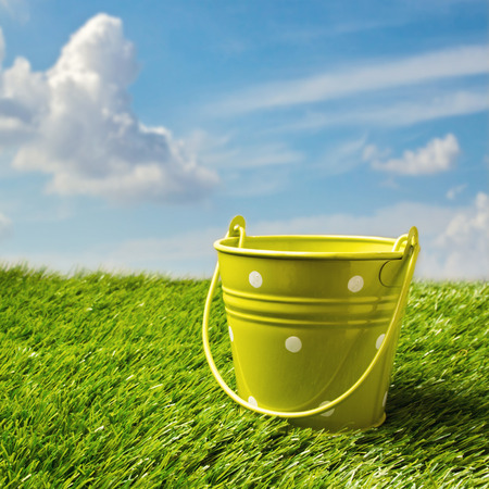 Green bucket on grass over blue skyの写真素材
