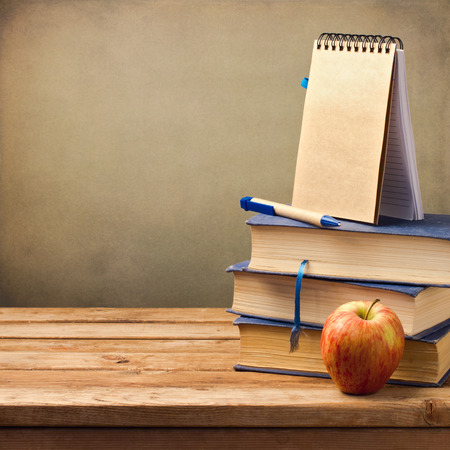 Back to school concept. Old books with apple and note book on wooden table.の写真素材