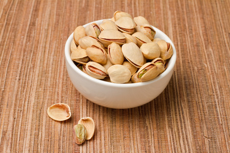 Pistachios nuts in bowl over tableclothの写真素材