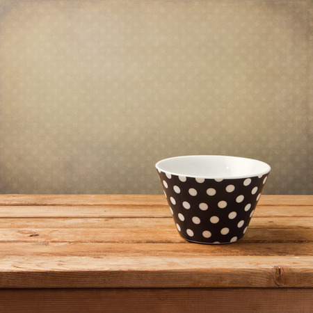 Empty polka dots bowl on wooden table over retro backgroundの写真素材