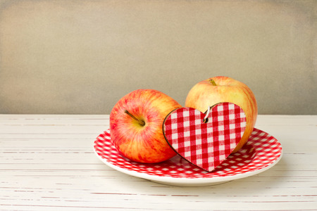 Fresh apples on checked plate on white wooden tableの写真素材