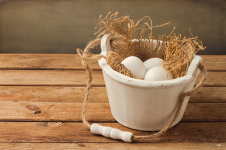 Wooden bucket with eggs over grunge backgroundの写真素材