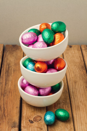 Easter chocolate eggs in bowls over wooden backgroundの写真素材