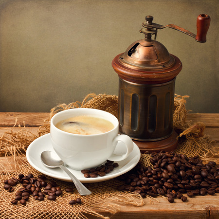 Coffee cup with vintage grinder on wooden tableの写真素材
