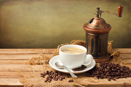 Vintage coffee grinder and coffee cup over wooden background over grunge backgroundの写真素材