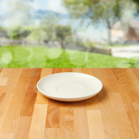 Empty plate on wooden table over nature backgroundの写真素材
