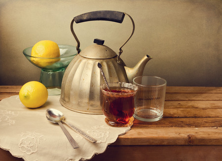 Vintage teapot with lemons and tea on wooden tableの写真素材
