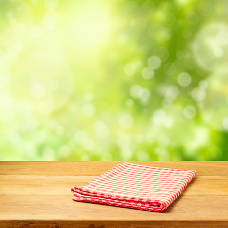 Empty wooden table with tablecloth over graden bokeh backgroundの写真素材