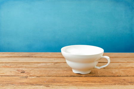 Empty coffee cup on wooden table over blue backgroundの写真素材