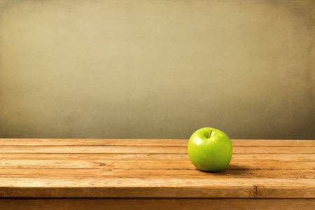 Green apple on wooden vintage table over grunge backgroundの写真素材