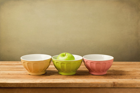 Colorful bowls with green apple on wooden vintage tableの写真素材
