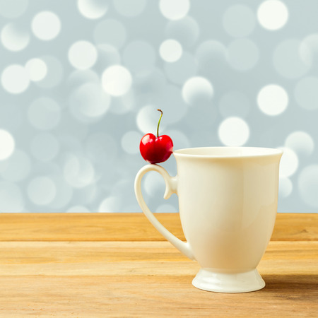 Single cherry on cup handle over bokeh backgroundの写真素材