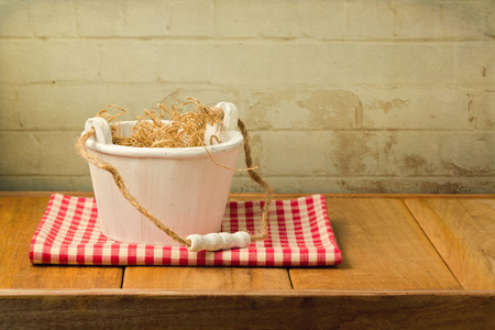 Wooden bucket on tablecloth on wooden table over brick stone wallの写真素材