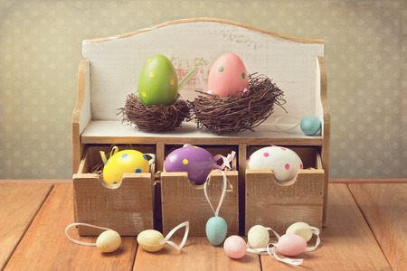 Easter eggs decorations on wooden table over retro background