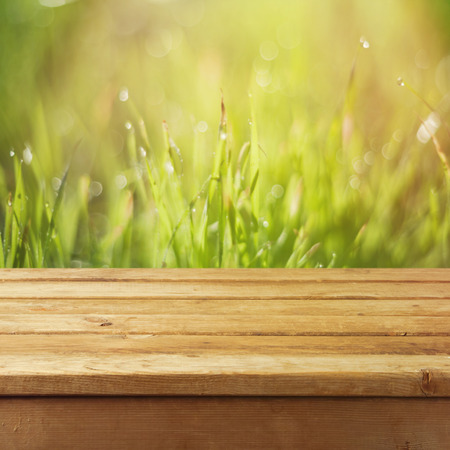 Empty wooden deck table over grass bokeh backgroundの写真素材