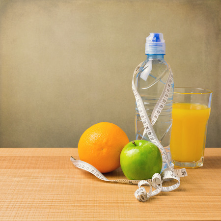 Healthy fruit, juice and bottle of water on wooden tableの写真素材