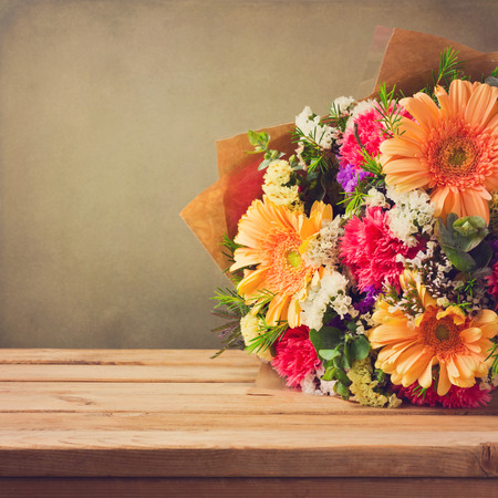Flower bouquet on wooden table over grunge backgroundの写真素材