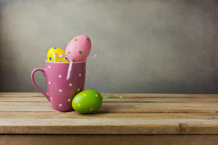 Easter eggs decorations in polka dots cup on wooden tableの写真素材