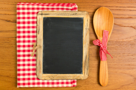 Chalkboard with wooden spoon on tabletop with tableclothの写真素材