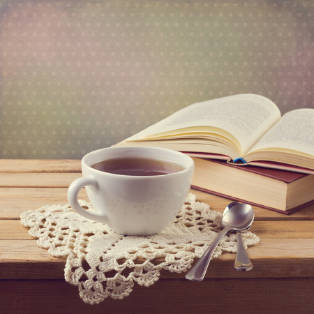 Cup of tea on crochet doily and vintage books with retro filter effectの写真素材