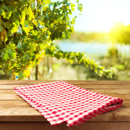 Empty wooden deck table with tablecloth over vineyard bokeh backgroundの写真素材