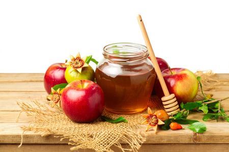 Honey, apple and pomegranate on wooden table over white backgroundの写真素材