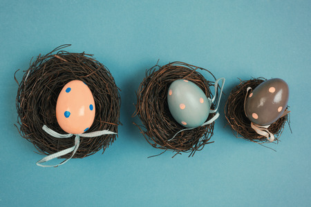 Easter eggs decoration in bird nest on blue background with retro filter