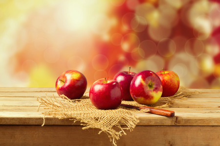 Apples on wooden table over autumn bokeh backgroundの写真素材