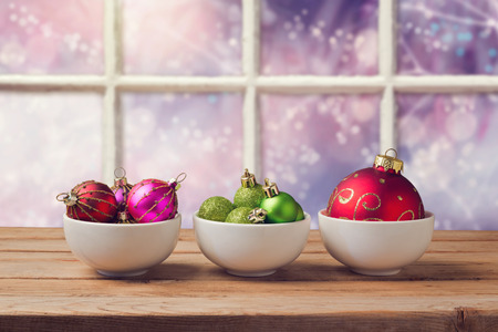 Christmas balls on wooden table over window backgroundの写真素材