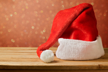 Santa Claus hat on wooden table over bokeh backgroundの写真素材