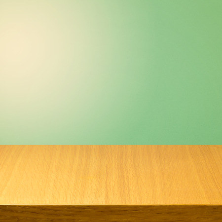 Empty wooden modern table over green solid color backgroundの写真素材