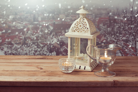 Vintage lantern with candles over winter town background with copy spaceの写真素材