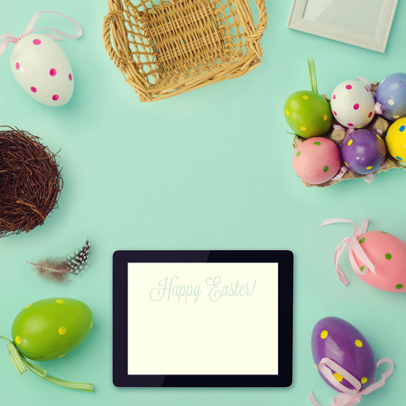 Easter holiday background with retro filter effect. Easter eggs decorations and tablet. View from aboveの写真素材