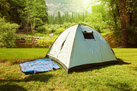 Camping tent on grass over beautiful forestの写真素材