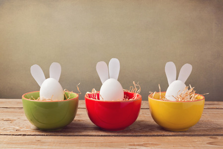 Easter holiday eggs with bunny ears on wooden tableの写真素材